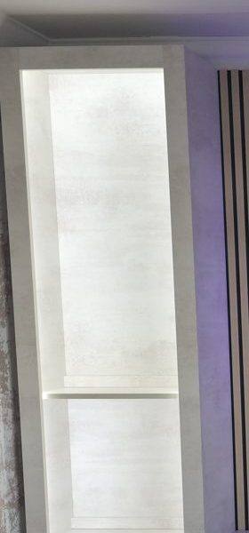 Illuminated upright display cabinet column beside a media wall