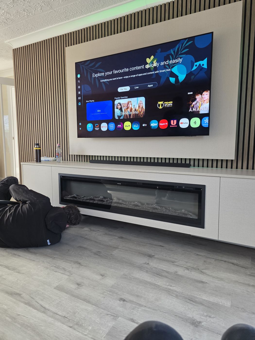 Wide Fife media wall, oak slats, cream concrete panel, green LED glow and long floating cabinet with electric fire.