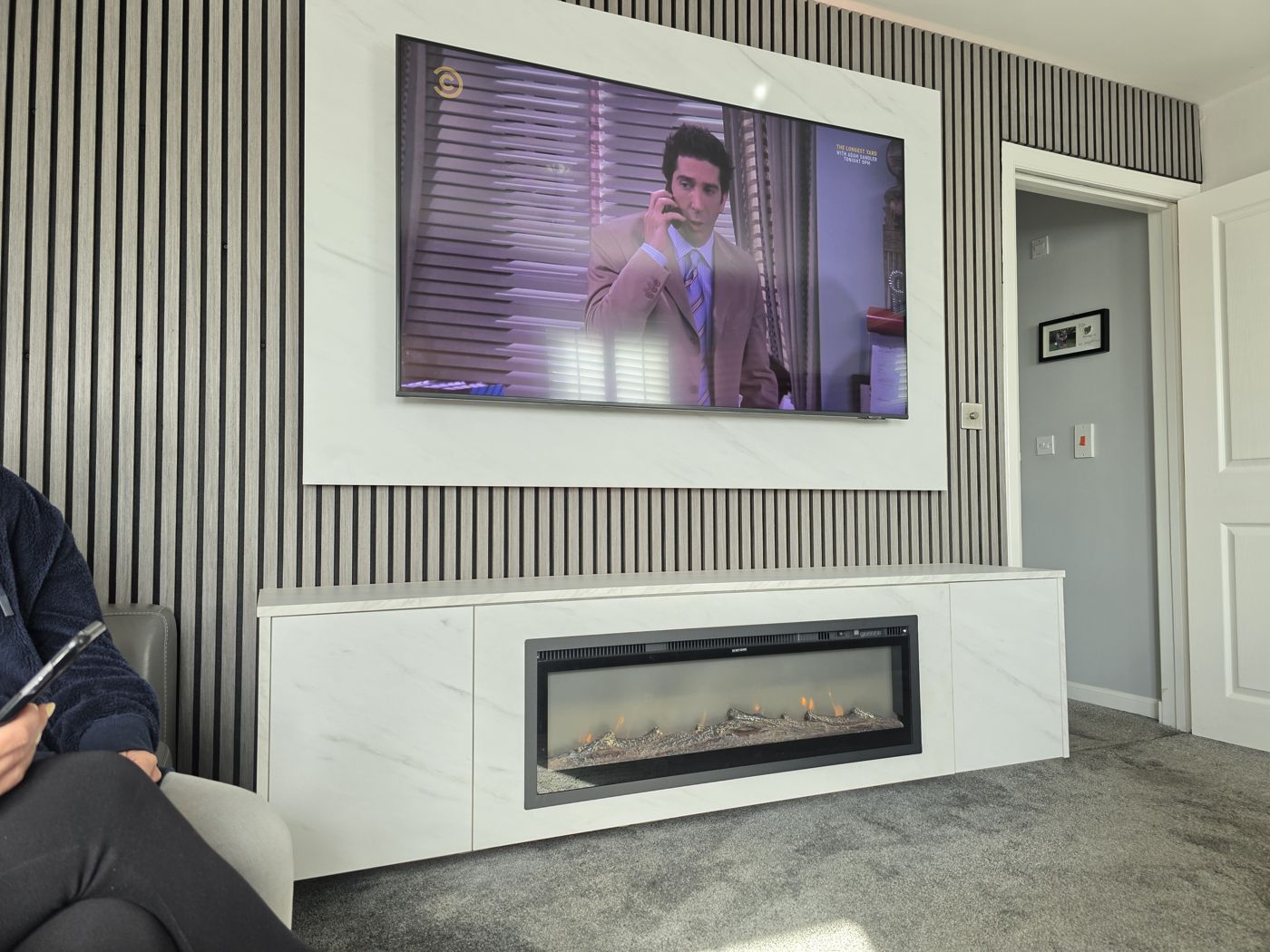 Side view of Glasgow white marble media wall, grey slats and long electric fire in the floating marble cabinet.