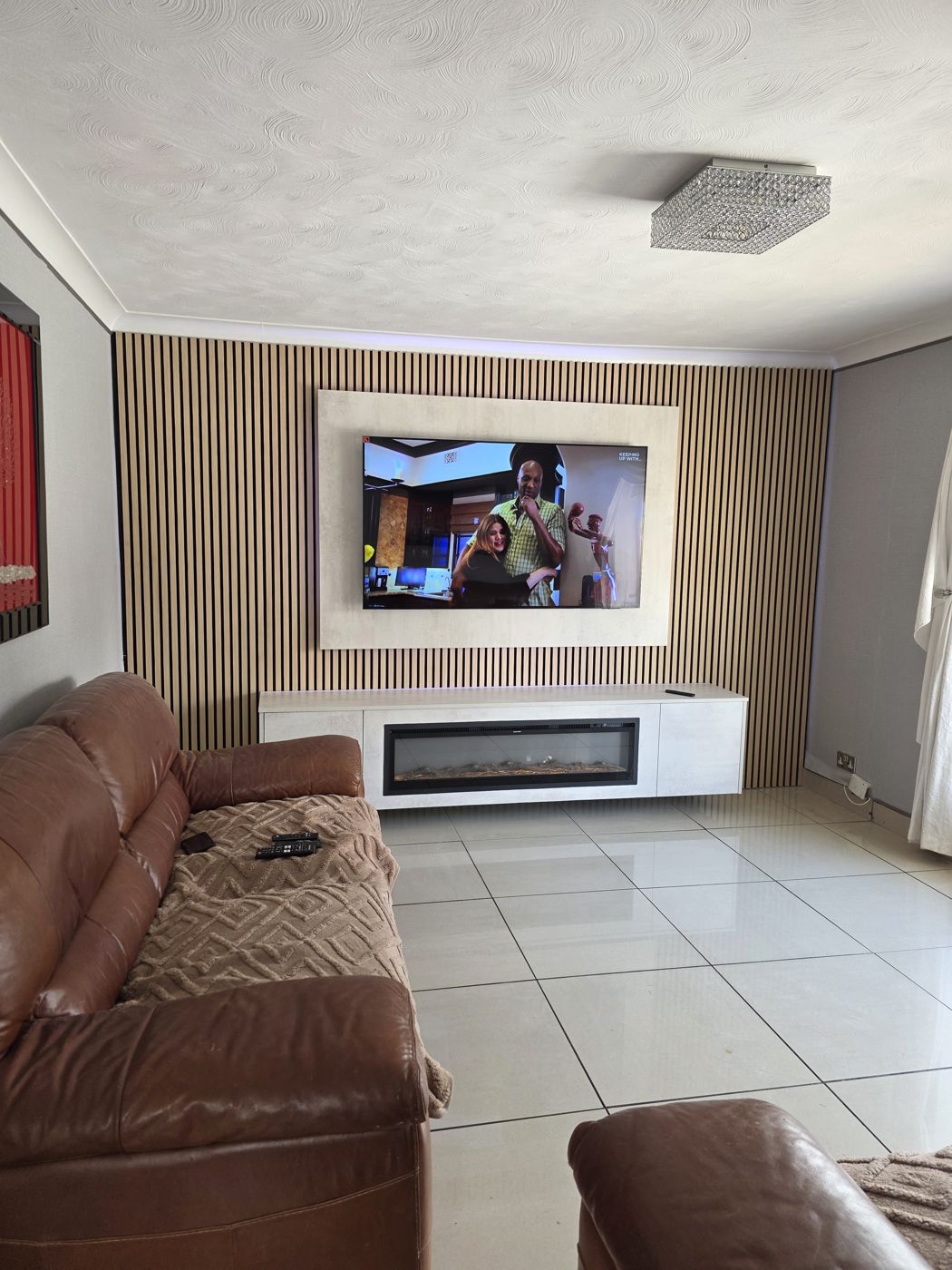 Wide Lanarkshire media wall, cream concrete panel, oak slats and long electric fire in the floating cabinet below.