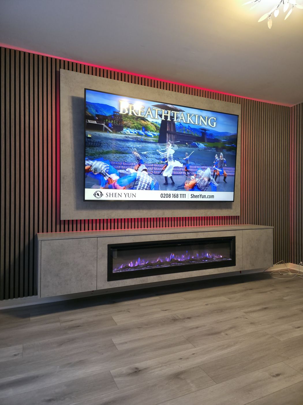 Paisley grey concrete media wall with charcoal slat panelling, a long purple-flame electric fire and warm red LED lighting