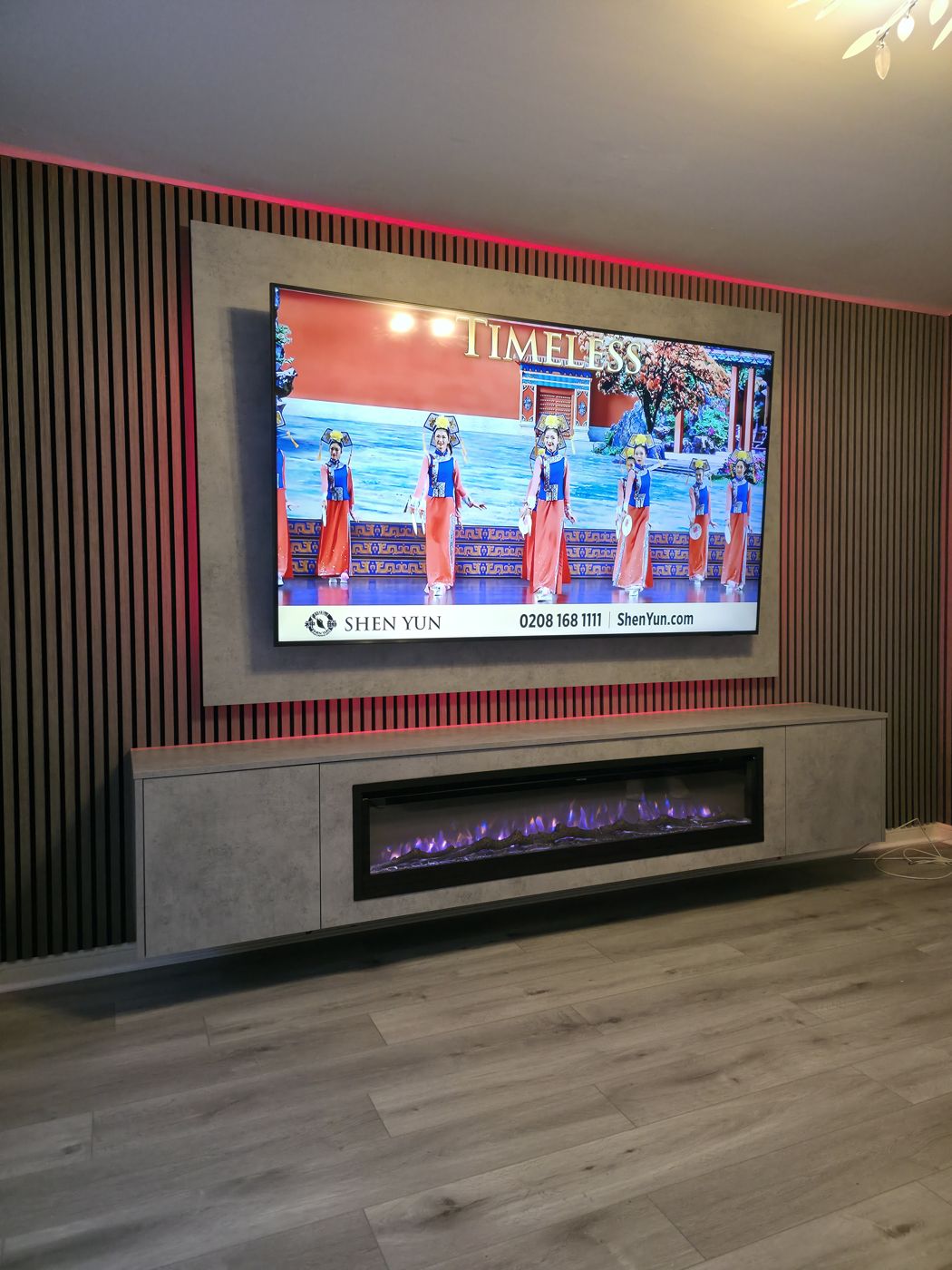 Paisley concrete-effect media wall with slatted panel, long electric fire and red LED glow behind the wall-mounted TV