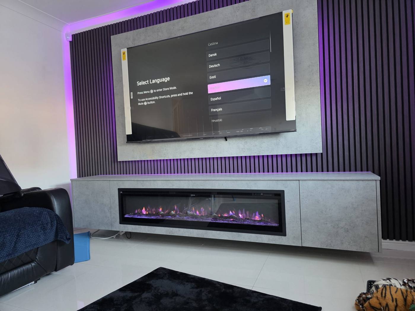 Concrete-effect floating cabinet and dark slat wall with purple LED backlighting