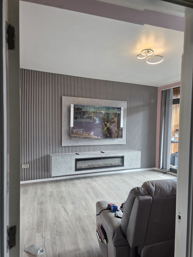 Angled view of the Clydebank Light Grey Chicago Concrete media wall through the doorway, charcoal slats and long electric fire, by MPS Media Walls.