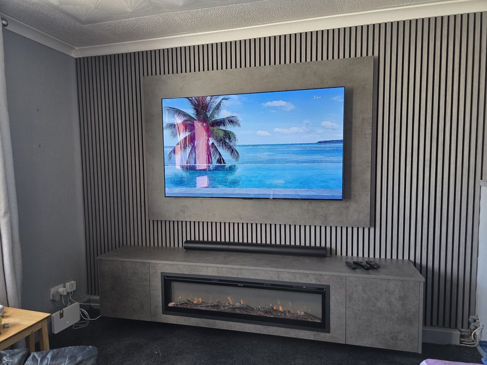 Wide room view of a dark grey Chicago concrete media wall in Girvan with slats, soundbar and amber electric fire, by MPS Media Walls.