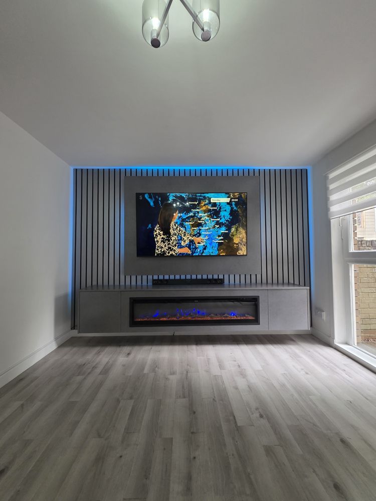 Angled view of the cubanite grey media wall in Glasgow, slatted panel, blue LED glow and blue-flame electric fire, by MPS Media Walls.