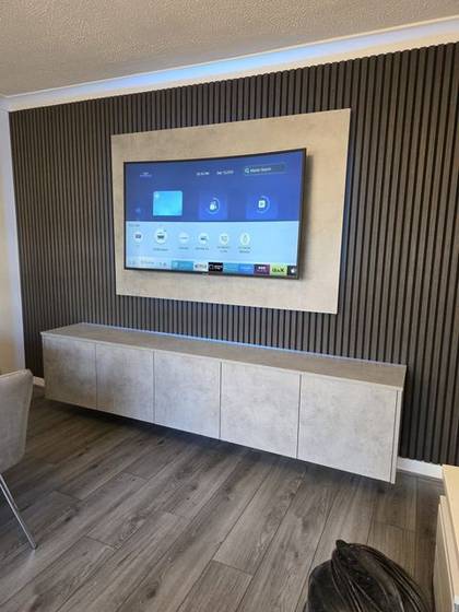Dark grey slat media wall with stone-effect TV panel and floating cabinet