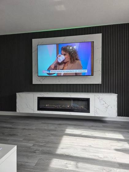 Black slat media wall with white marble panels and linear electric fire