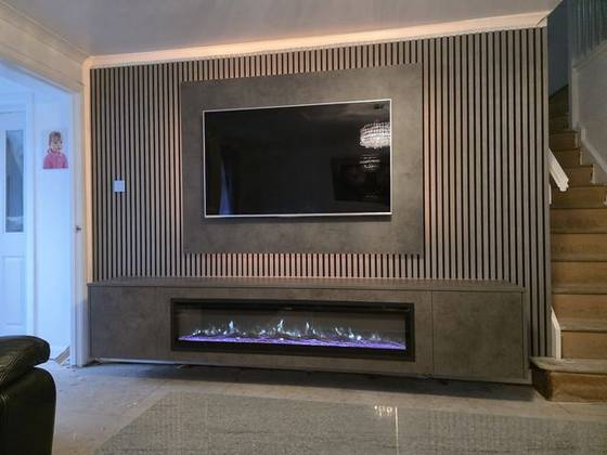 Full-width grey slat media wall with concrete-effect cabinet and wide electric fire