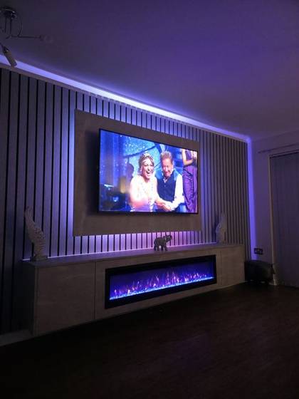 White slat media wall bathed in purple LED light with crystal-effect fire