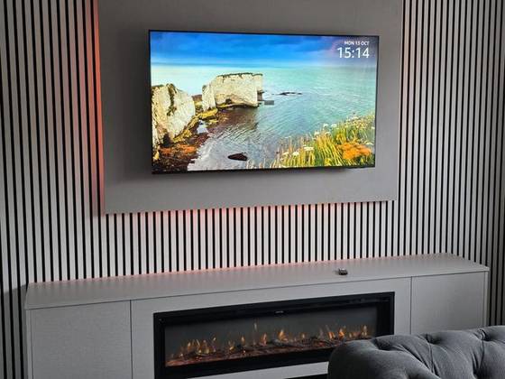 Monochrome slat wall with warm LED backlight, TV and log-effect fire
