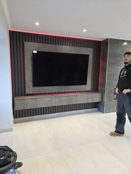 Red LED backlit slat media wall under construction with tiled chimney breast