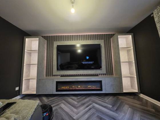 Concrete-effect media wall with black slat panels, linear fire and lit shelving