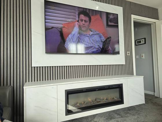 Marble-effect media wall with grey slat panelling and linear log-effect fire