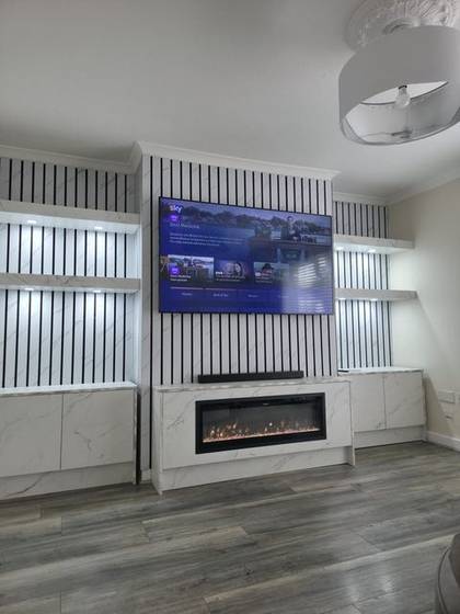 White marble slat media wall with illuminated niches and linear electric fire