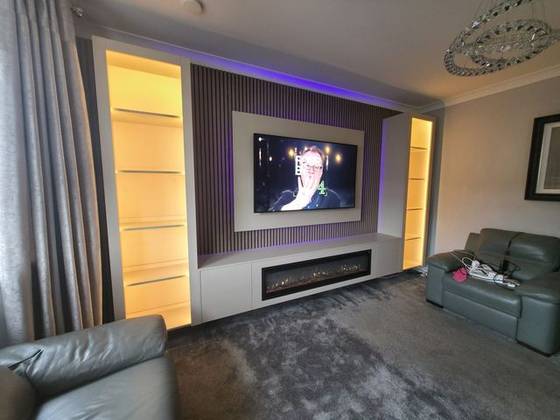 Walnut slat media wall with amber-lit shelving, purple LEDs and linear fire